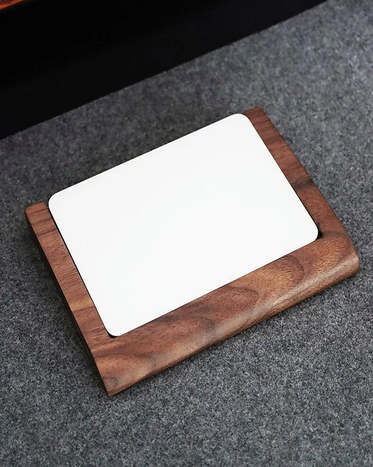 A solid walnut tray on grey felt, showing the grain running through the wood